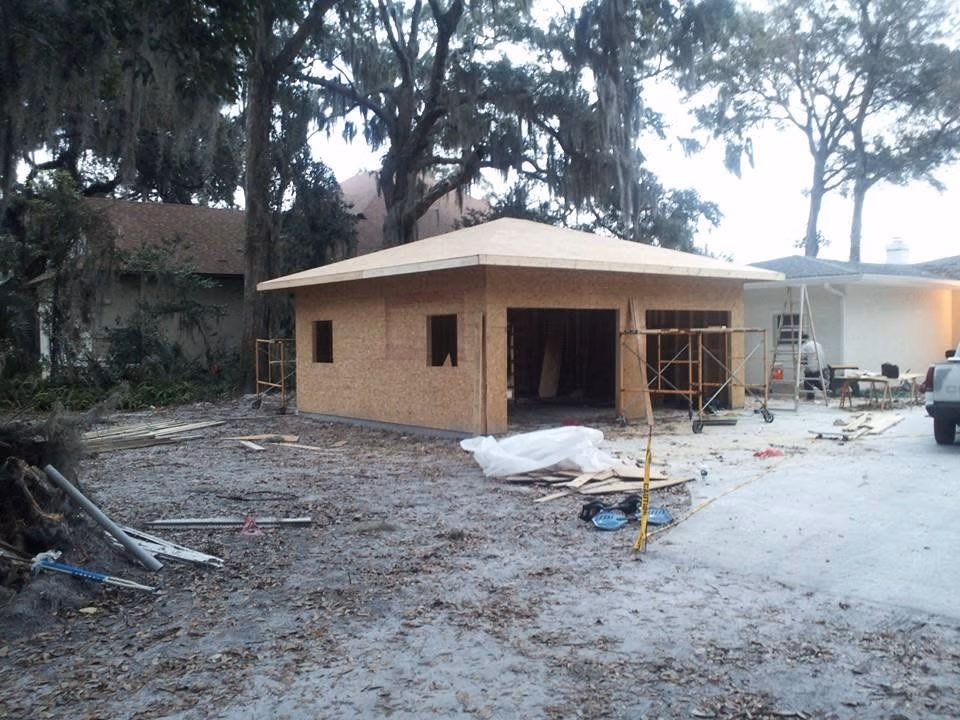Wood-framed house under construction with scaffolding and construction materials around the site.