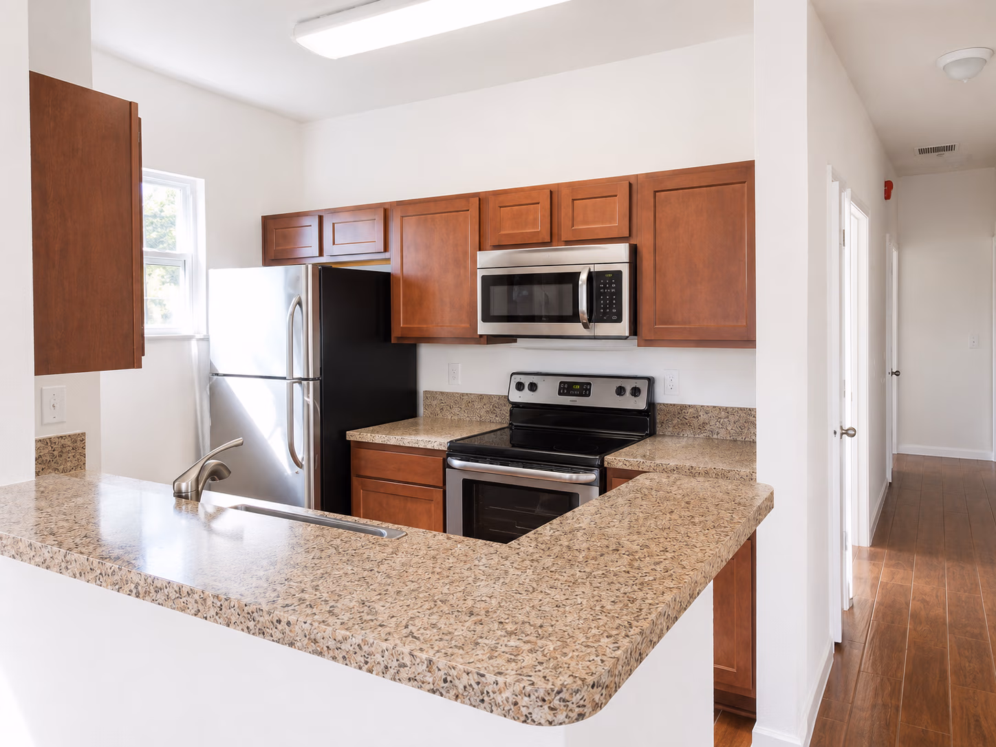 Kitchen with brown cabinets, granite countertops, stainless steel refrigerator, stove, and built-in microwave.