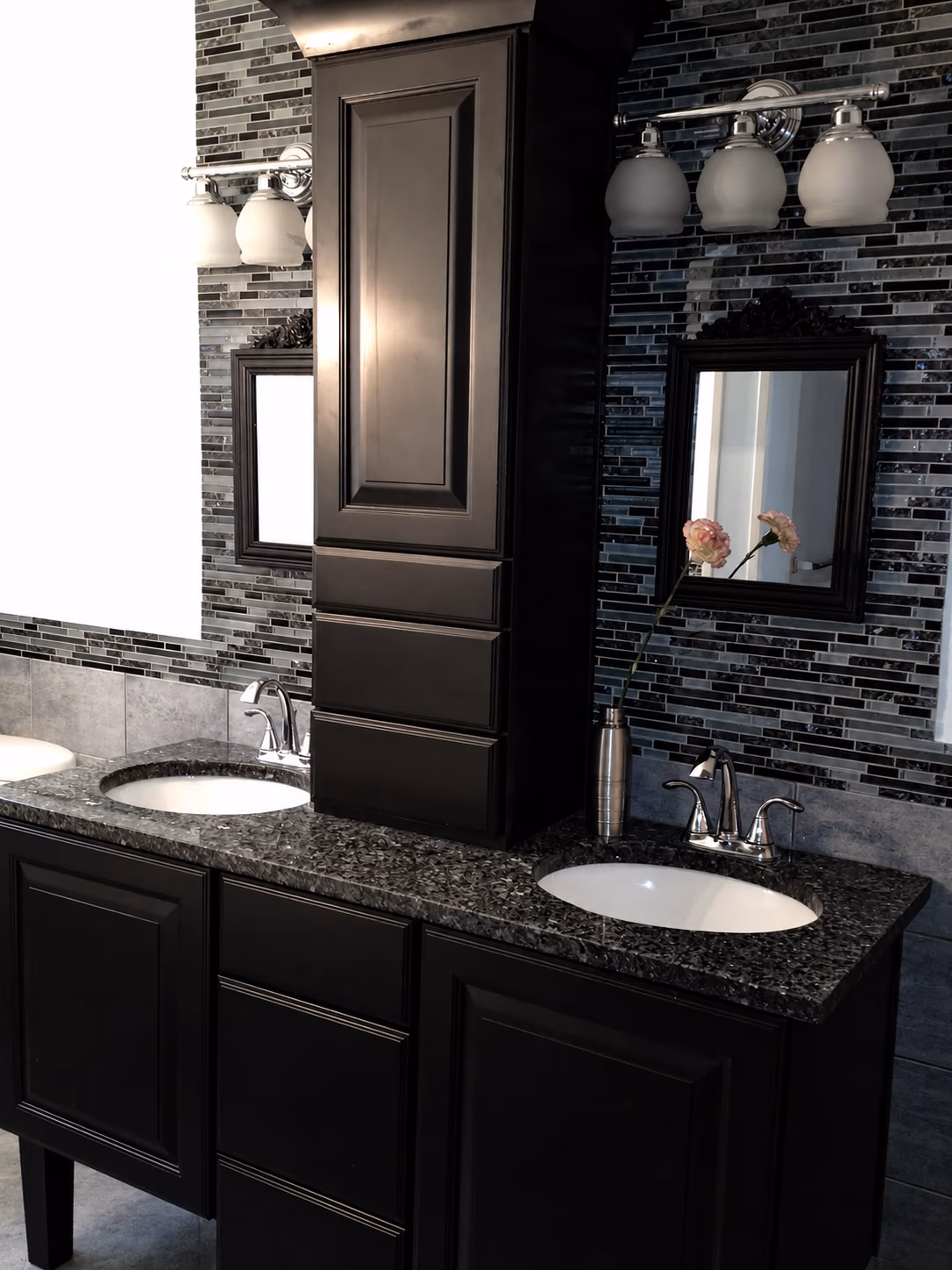Modern double bathroom vanity with dark cabinets, granite countertop, two sinks, mirrors, and light fixtures.