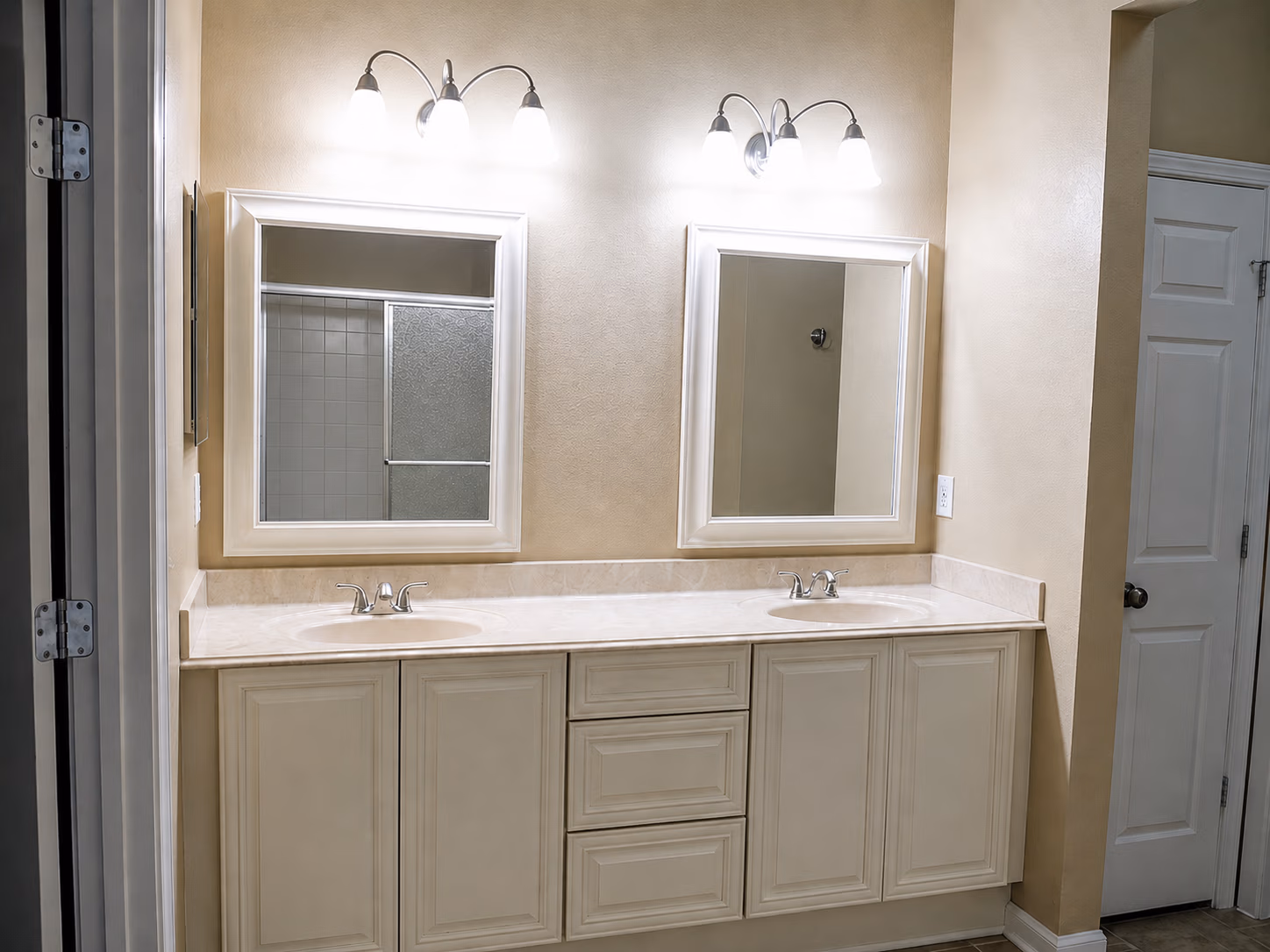 Bathroom vanity with two sinks, two mirrors, and three-light wall fixtures above each mirror.