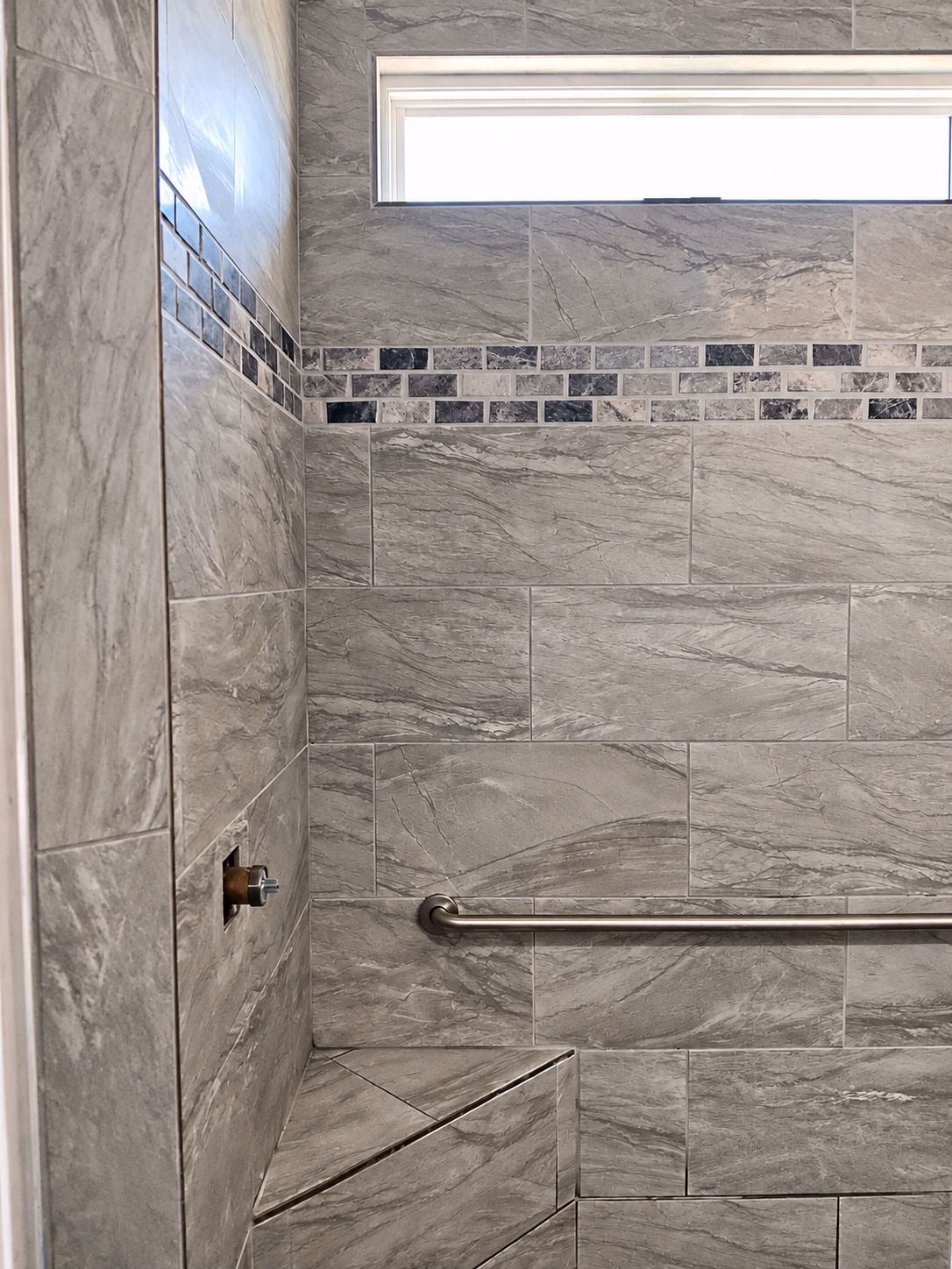 Walk-in shower with a built-in bench and a grab bar