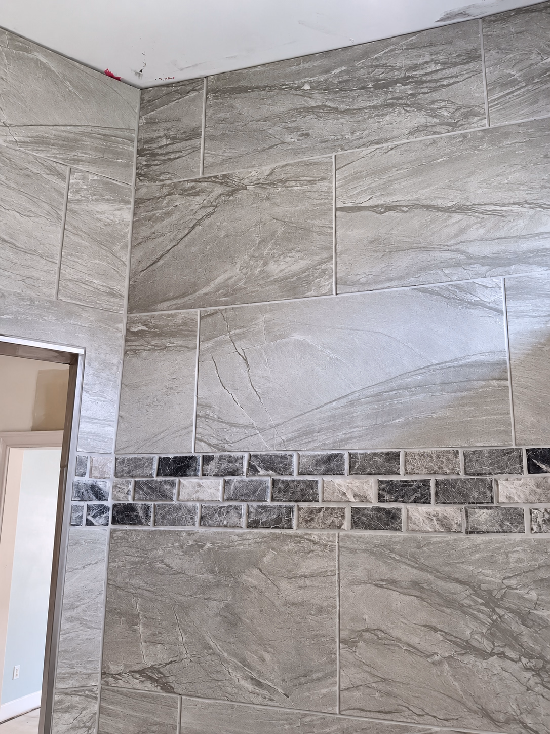 Tiled walk-in shower with a patterned accent wall