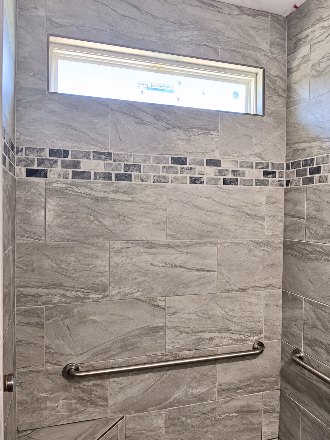 Tiled shower with a window and a decorative accent band