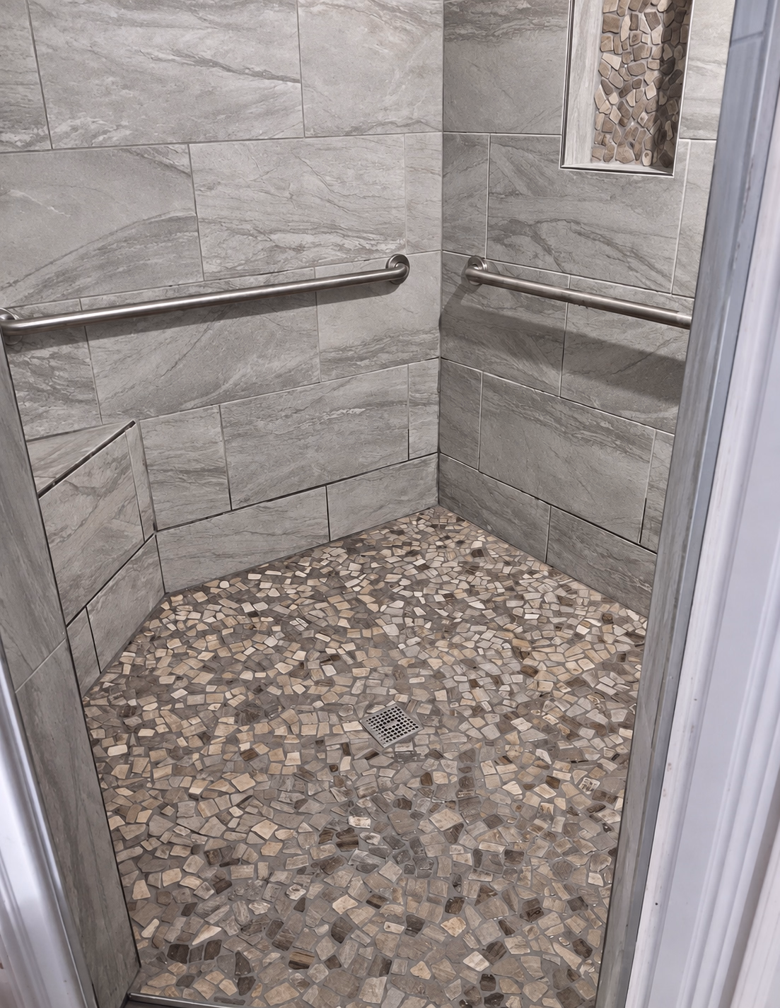 Finished walk-in shower with a pebble stone floor and tiled walls
